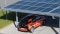 The picture shows a carport with PV modules on the roof and an electric car being charged.